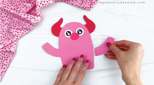 hands gluing arms to valentine monster craft