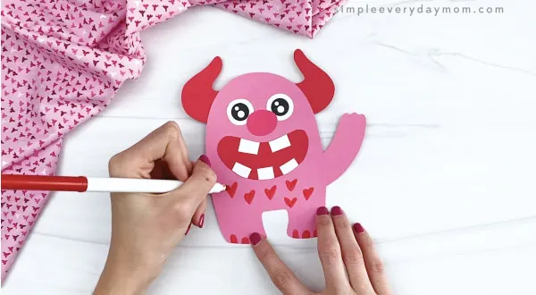 hand drawing hearts onto valentine love monster craft