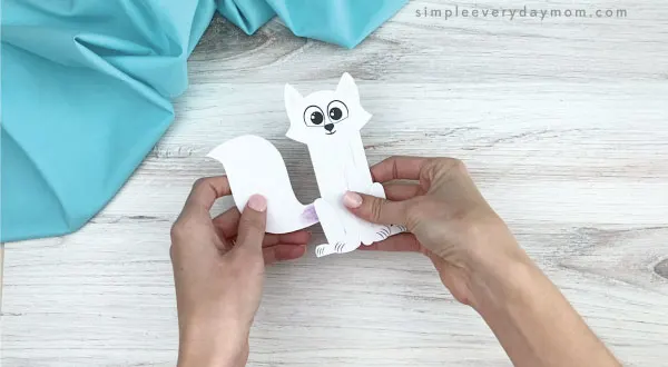 hands gluing tail to popsicle stick arctic fox