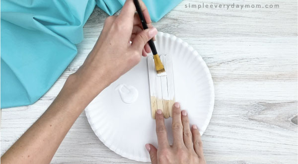 hands painting popsicle sticks white