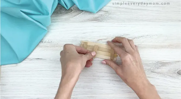 hands gluing popsicle sticks together