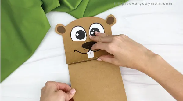 hands gluing body to paper bag groundhog craft