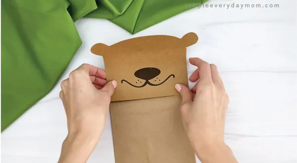 hands gluing head to paper bag groundhog craft