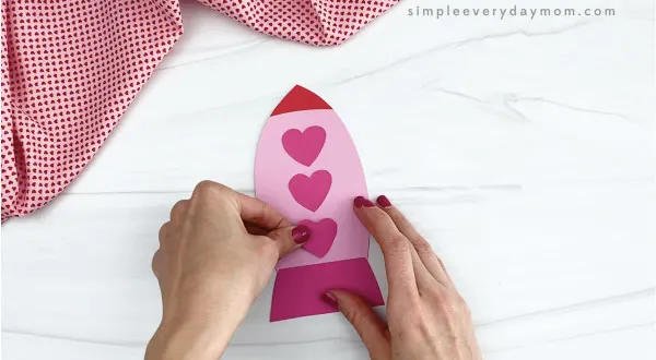 hands gluing hearts to rocket valentine craft