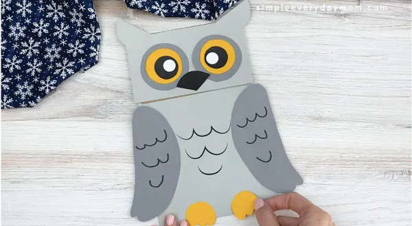 hands gluing feet to paper bag owl craft