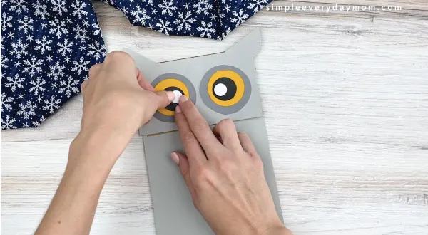 hands gluing eyes to paper bag owl craft