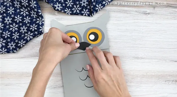 hands gluing beak to paper bag owl craft