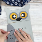 hands gluing wings to paper bag owl craft