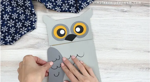 hands gluing wings to paper bag owl craft