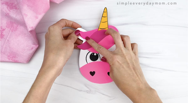 hand gluing ears onto unicorn card craft