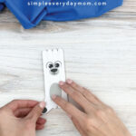 hands gluing outer legs onto popsicle stick polar bear craft