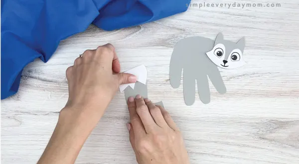 hand gluing tail tip to handprint arctic fox craft