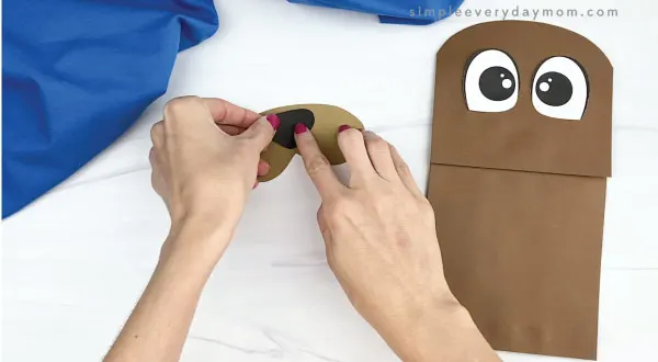 hand gluing nose to paper bag walrus mouth