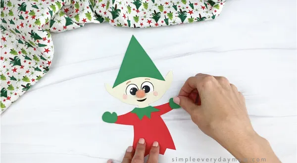 hands gluing mitten onto paper elf craft