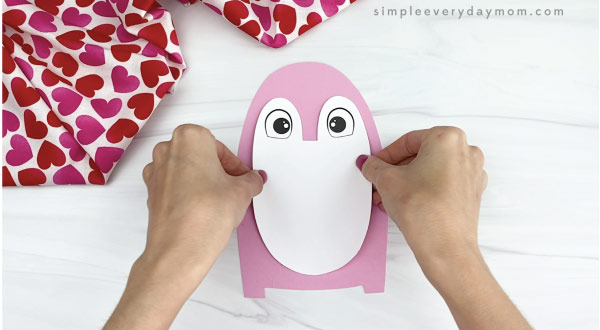 hand gluing body onto penguin valentine craft