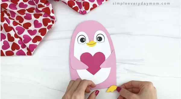 hand gluing feet onto penguin valentine craft