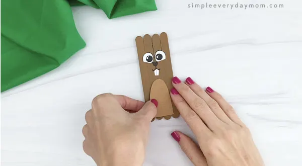 hand gluing belly onto popsicle stick groundhog craft