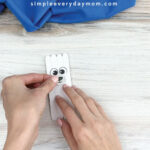 hands gluing mouth and nose onto popsicle stick polar bear craft
