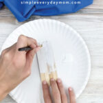 hands painting popsicle stick white