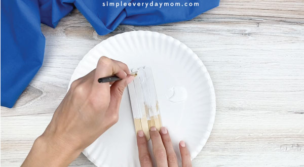 hands painting popsicle stick white