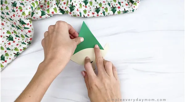 hands gluing hat onto paper elf craft