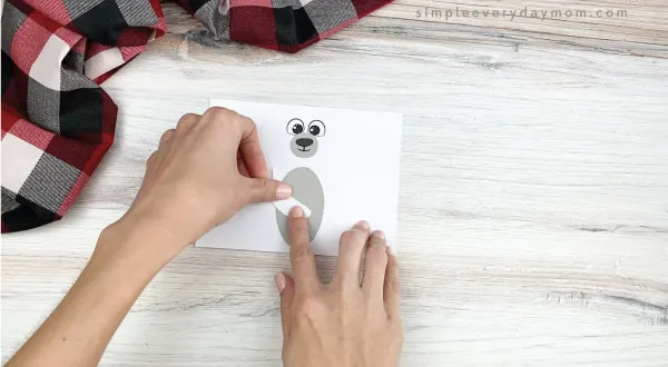 hands gluing arms to toilet paper roll polar bear craft