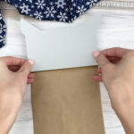 hands gluing paper bag owl face to brown paper bag