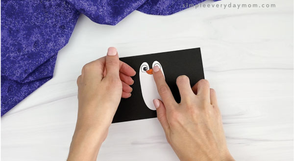 hands gluing beak to toilet paper roll penguin craft