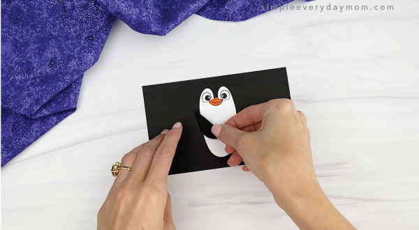 hands gluing arms to toilet paper roll penguin craft