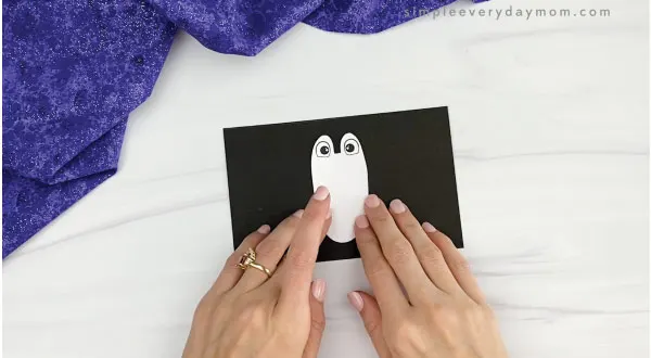 hands gluing belly to toilet paper roll penguin craft