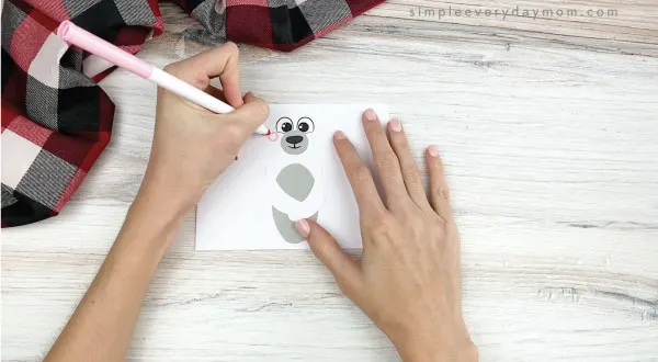 hands drawing cheeks onto toilet paper roll polar bear craft