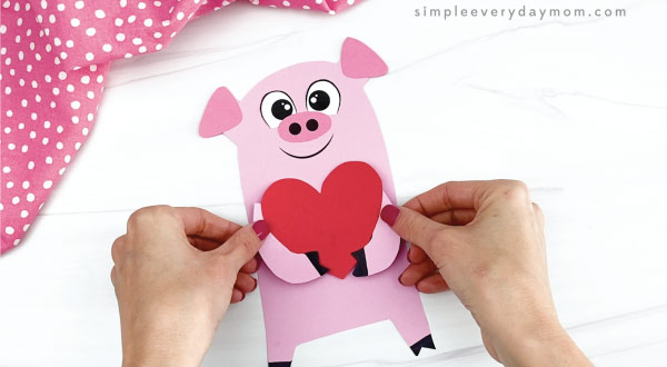hand gluing arms to pig valentine craft
