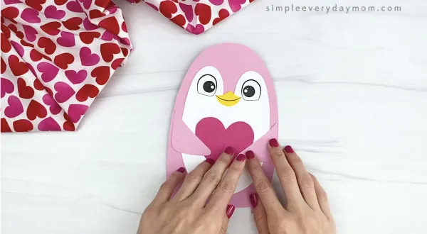hand gluing arms onto penguin valentine craft