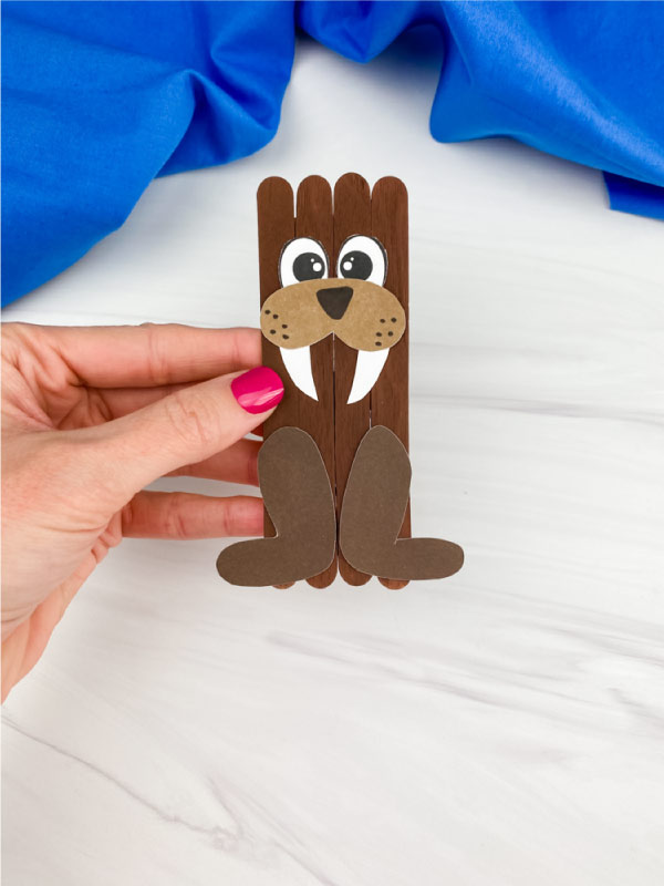 hand holding popsicle stick walrus craft