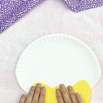 hand gluing bowtie to paper plate Easter bunny craft