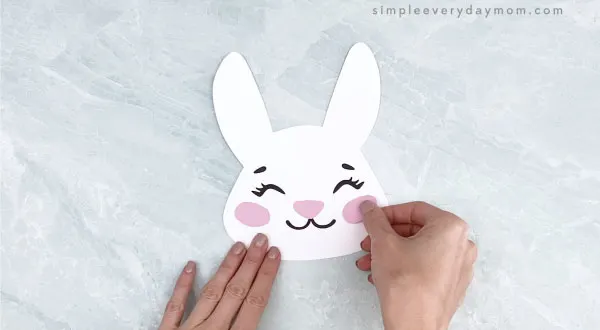 hands gluing cheeks to Easter bunny headband craft