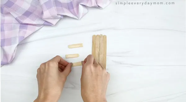 hand stretching glue dot onto cut popsicle stick