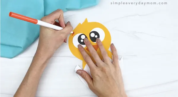 hands drawing eyebrows onto hatching chick craft