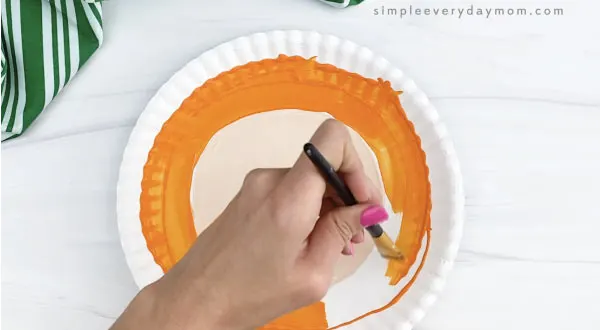 hand painting outer ring of paper plate orange