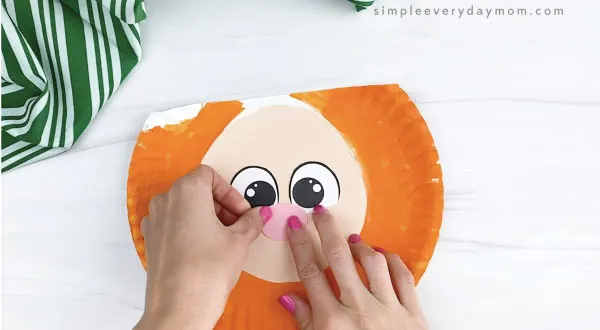 hand gluing nose to paper plate leprechaun craft