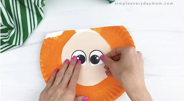 hand gluing eyes to paper plate leprechaun craft