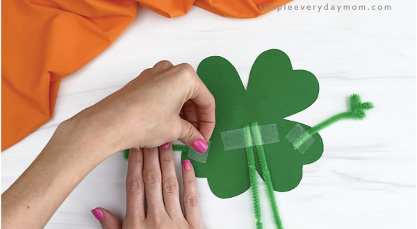 hand taping pipe cleaner arms to shamrock craft