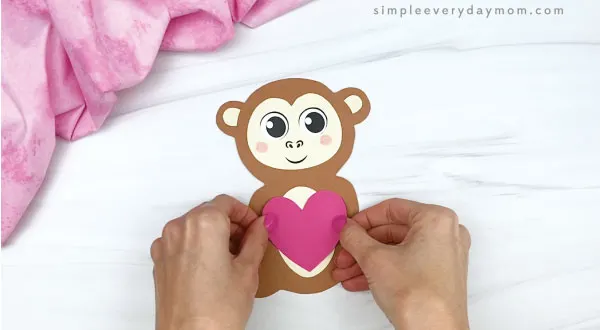 hand gluing heart to monkey valentine craft