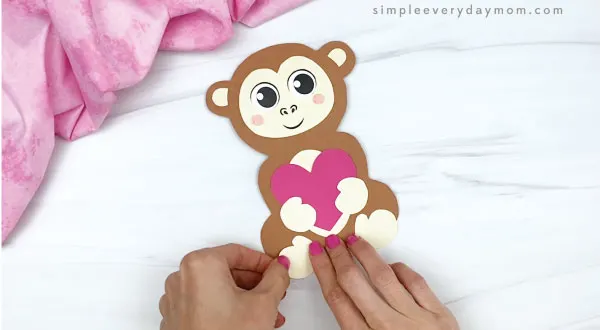 hand gluing feet to monkey valentine craft