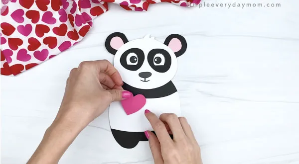 hand gluing heart to panda valentine craft