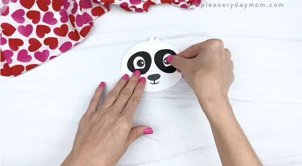 hand gluing eyes to panda valentine craft