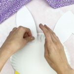 hand taping ears to back of paper plate