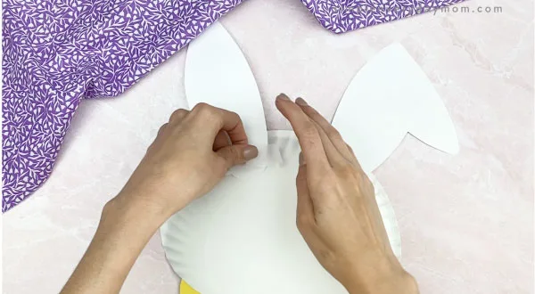 hand taping ears to back of paper plate