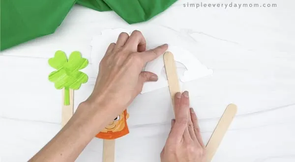 hand taping popsicle stick to back of puppet