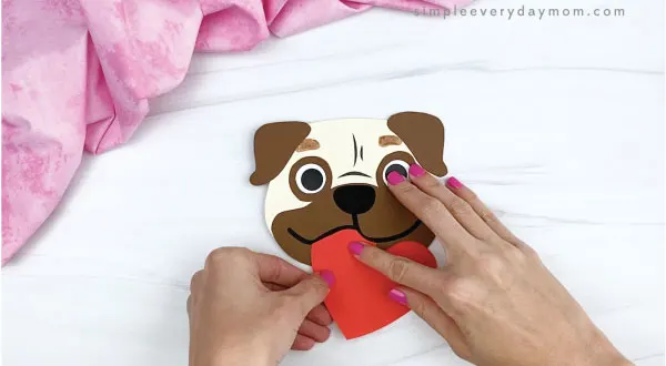 hands gluing heart onto puppy valentine craft